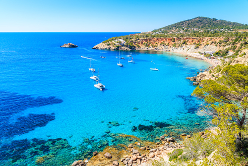 📸Veleiros na baía de Cala d'Hort com bela água do mar azul, ilha de Ibiza, Espanha.
