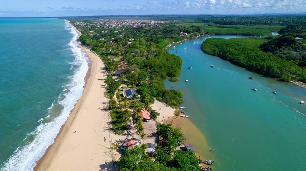 Vista aérea da praia de Caraíva, Porto Seguro, Bahia, Brasil. Barracas coloridas de praia, mar e rio.