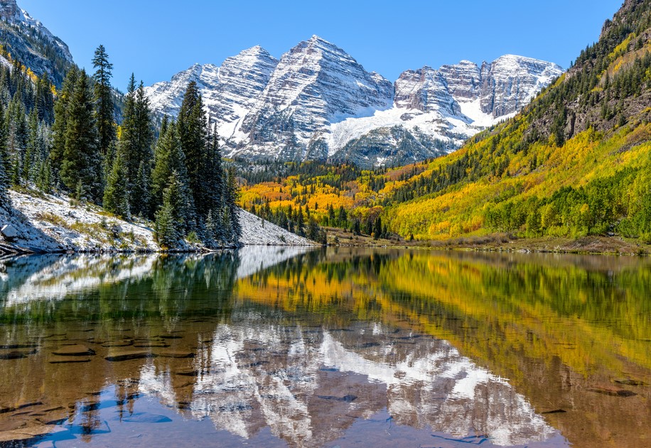 Uma visão ampla do meio-dia de outono de Sinos Maroon revestidos de neve refletindo em cristalino Maroon Lake, Aspen, Colorado, EUA.